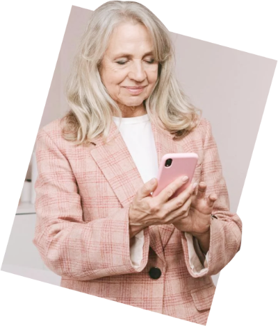A person in a smart dress jacket and shirt smiles while viewing something on their smartphone screen.