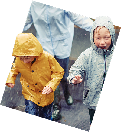 Two cheerful children dressed in raincoats, enjoying a rainy day outdoors.