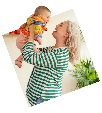 A joyful parents lifts a laughing baby into the air.
