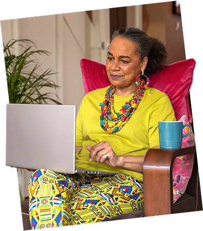 A person sits comfortably in a chair, working on a laptop with a thoughtful, focused expression.